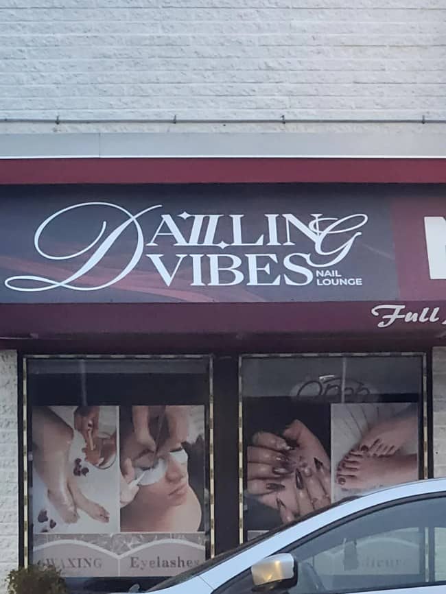 Nail salon store front sign with messy cursive lettering spelling out Darling Vibes.