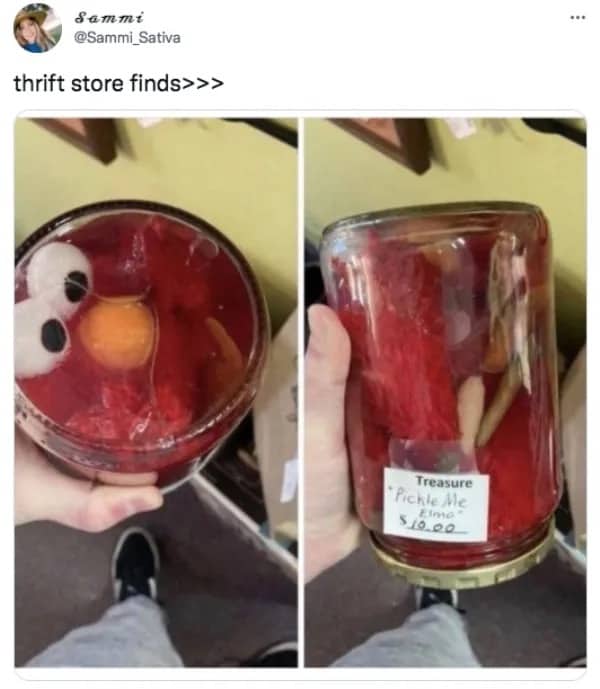 Glass jar labeled Pickle Me Elmo containing a red Elmo plush toy submerged in fluid.