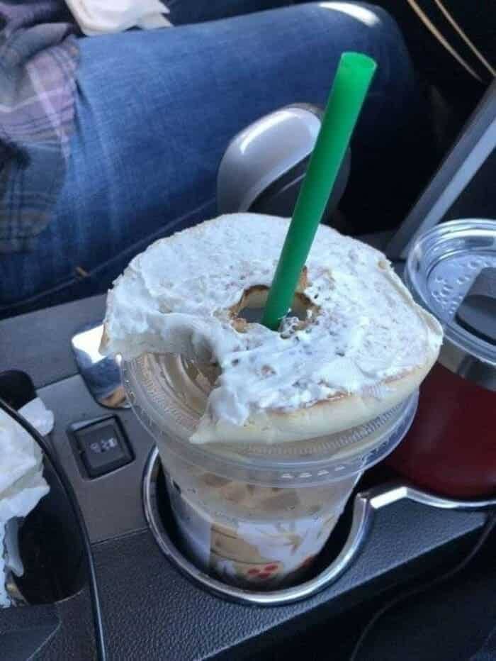 Cream cheese bagel resting on top of an iced coffee cup with straw.