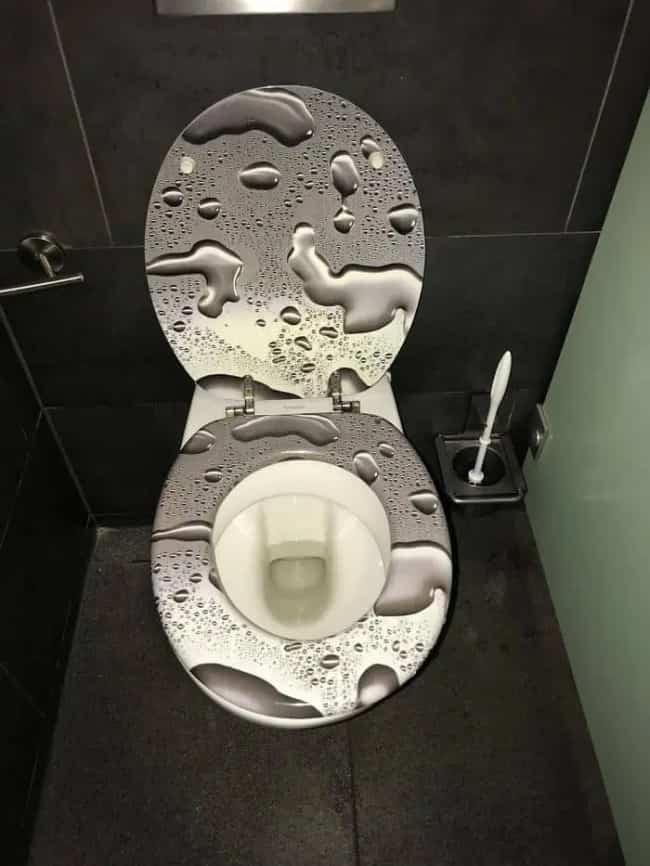 Toilet seat decorated with a realistic water drop pattern that constantly appears dangerously wet.