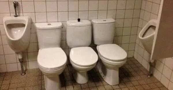 Multiple toilets and urinals placed closely together in a public bathroom with zero privacy stalls.