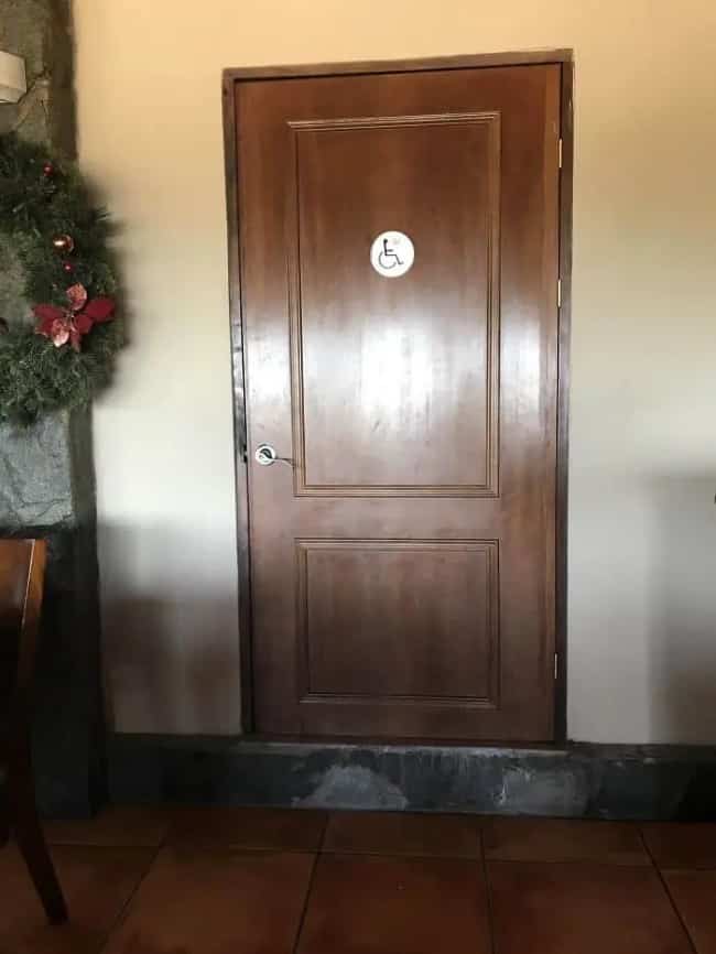 An accessible wheelchair bathroom door installed on a raised step without an entry ramp present.