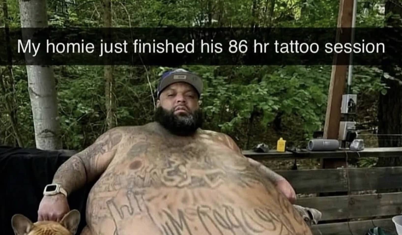 Shirtless man resting outdoors with extensive body tattoos next to a small dog meme.