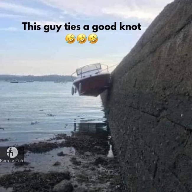 Small motorboat hanging suspended sideways against high seawall above water level.