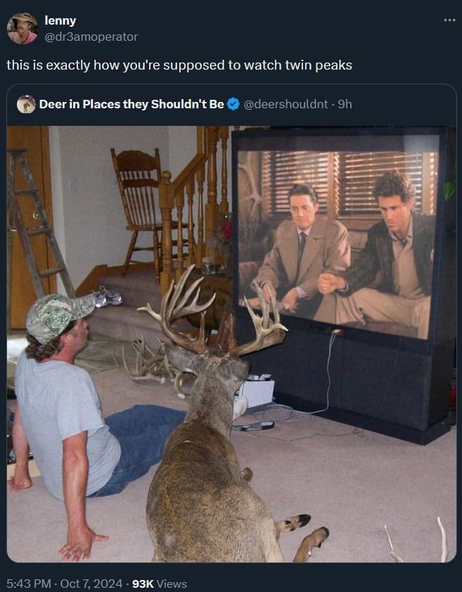 A surreal television viewing classic meme tweet showing a man watching Twin Peaks on a large cabinet TV sitting on the floor right beside a full-sized deer.