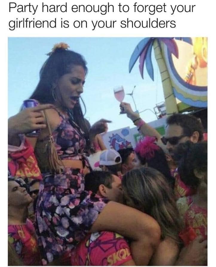 Crowd music festival photo of a man kissing a woman directly in front of him while completely oblivious that his girlfriend is sitting on his shoulders.