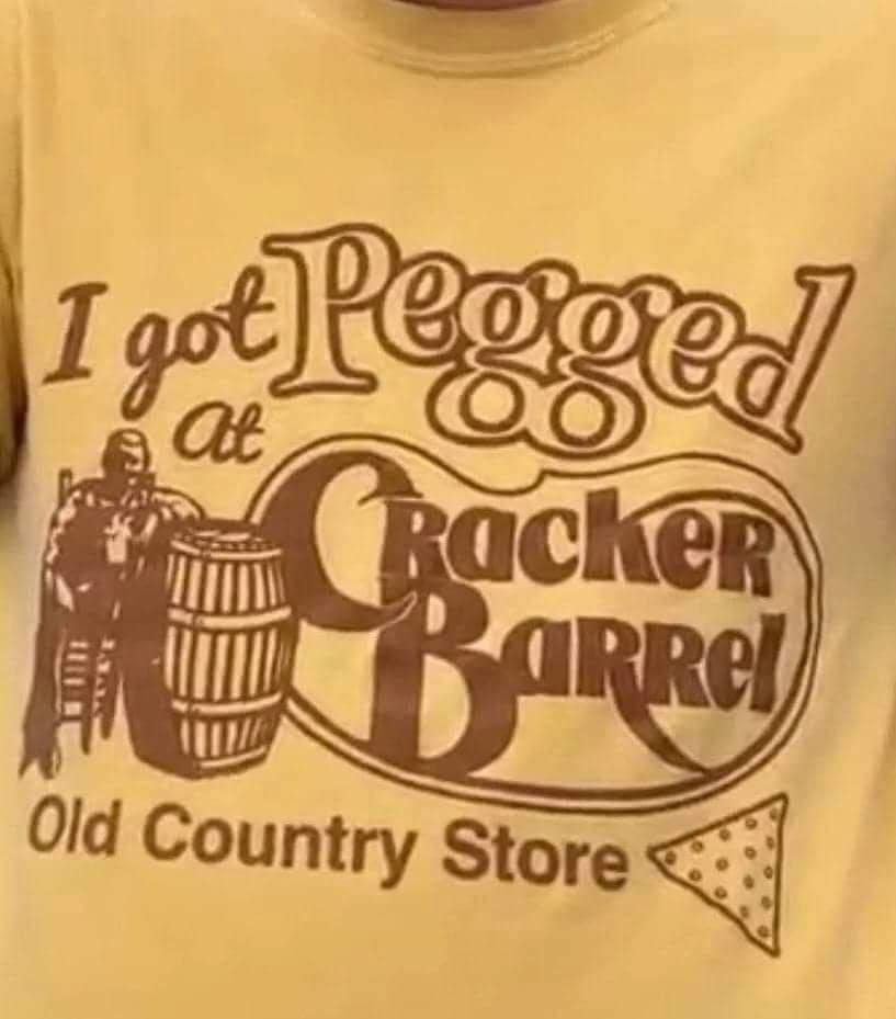 Close-up of a vintage yellow t-shirt parodying the famous restaurant logo to read "I got Pegged at Cracker Barrel Old Country Store."