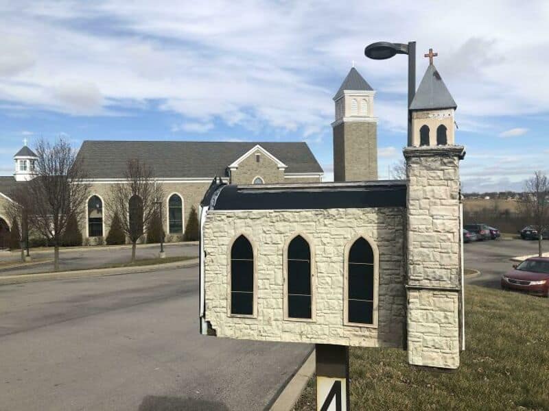 Detailed custom stone church cool mailbox standing directly across from an actual matching stone church building.
