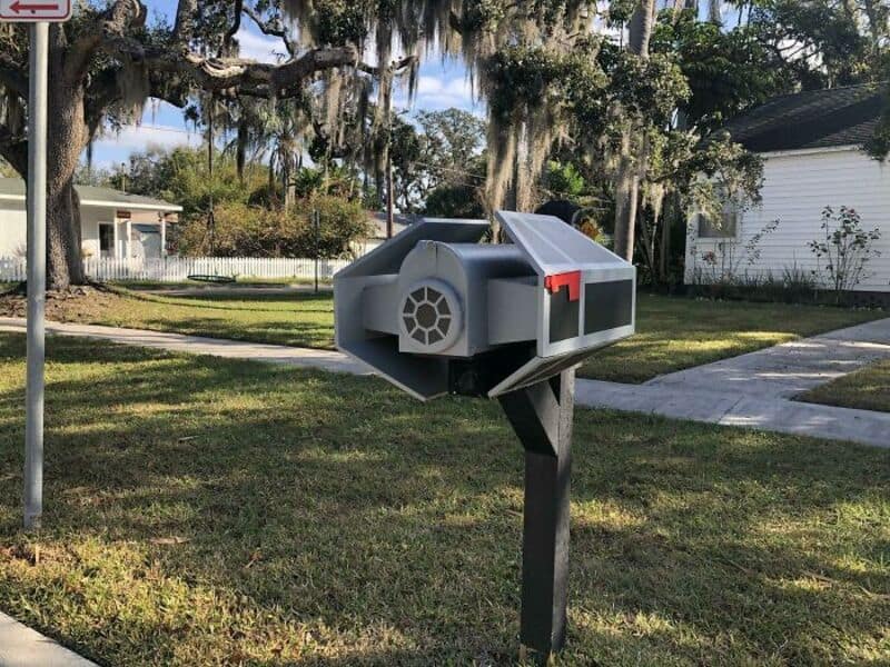 Star Wars TIE fighter custom mailbox mounted on a post in a suburban front yard.