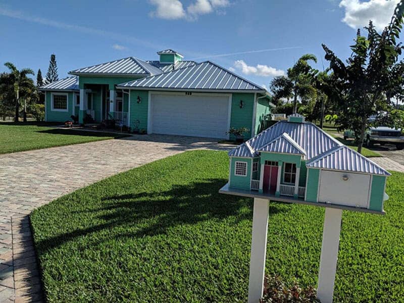 Custom replica mini house mailbox matching the architecture and teal paint of the house behind it.