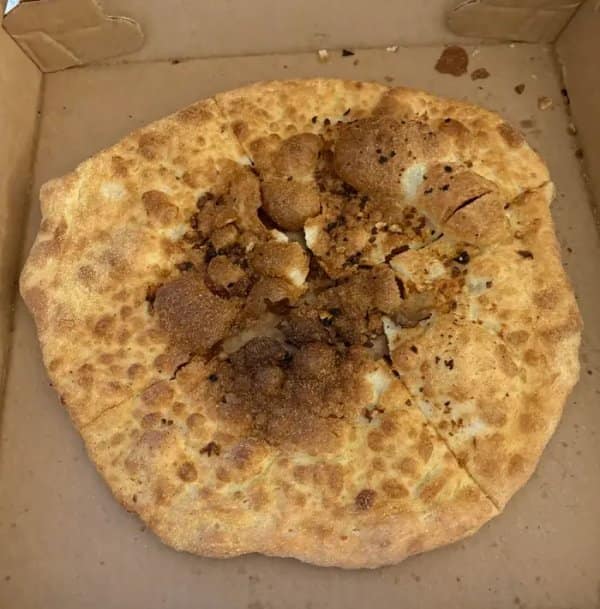 Cursed pizza delivery box containing a completely plain, dry dough crust with a massive burnt bubble crater in the middle and no sauce or cheese.