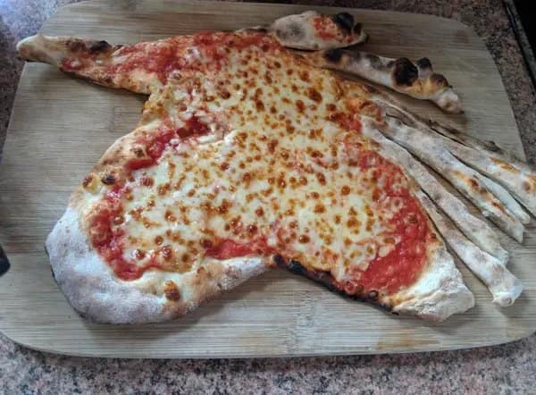 Cursed pizza dough stretched out on a wooden cutting board resembling a grotesque hand with long, burnt dough fingers extending from one side.