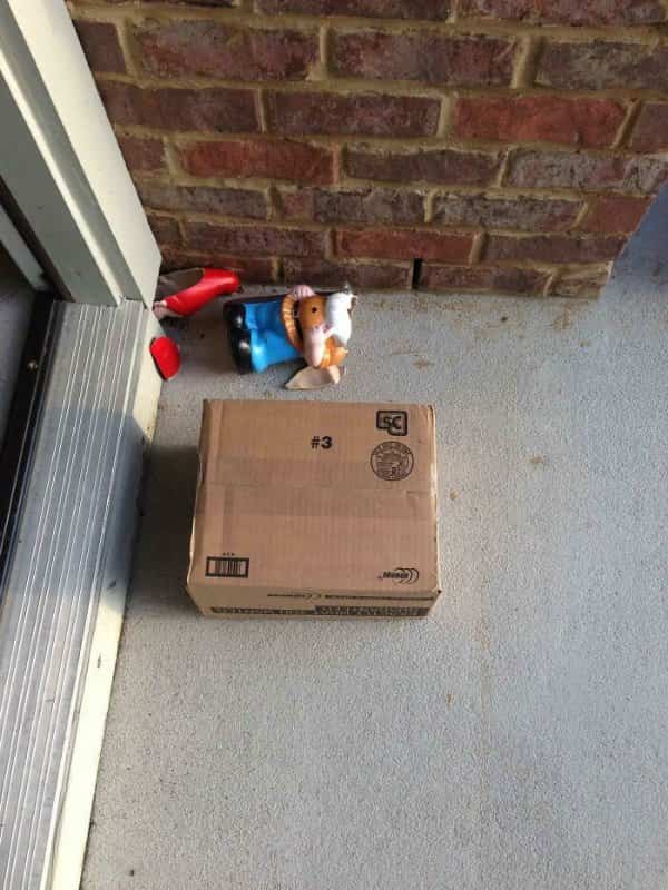 Cardboard package delivered on a porch right next to a smashed garden gnome statue fail.