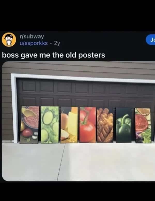 Subway restaurant food posters lined up along a residential garage door outside.