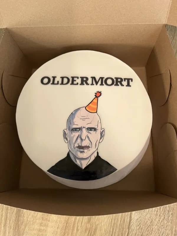 Harry Potter birthday cake decorated with Voldemort wearing party hat labeled Oldermort funny meme.