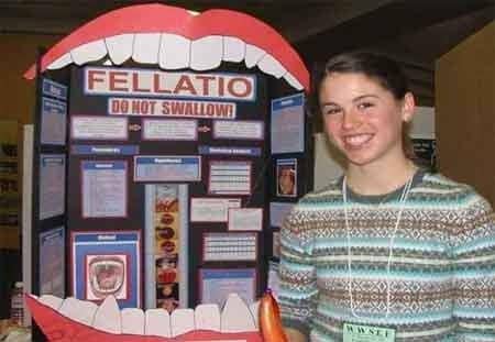 Girl smiling proudly beside a detailed science fair display about fellatio anatomy.