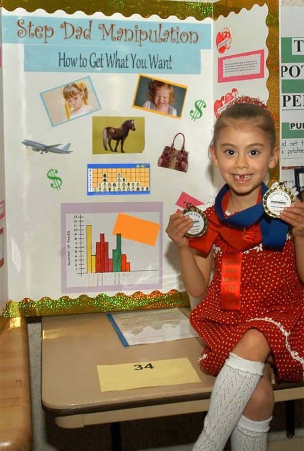 oung girl proudly holding science fair medals next to Step Dad Manipulation board.