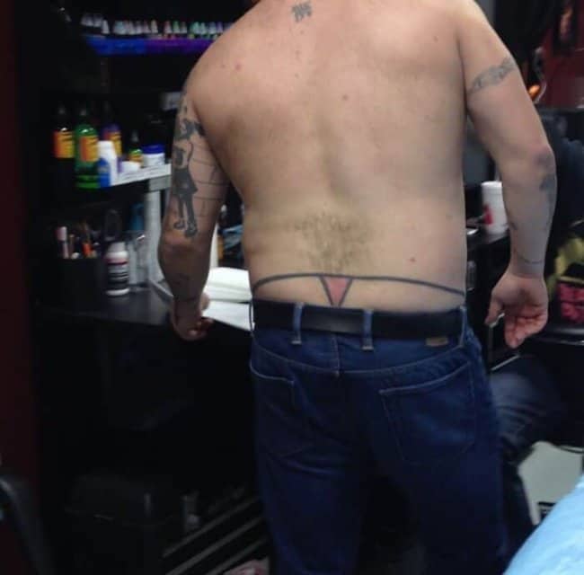 Man displaying a humorous lower back tattoo depicting a delicate pink thong funny tattoos
