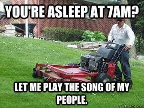 Man pushing heavy commercial lawn mower up steep grassy hill for early morning lawn meme.