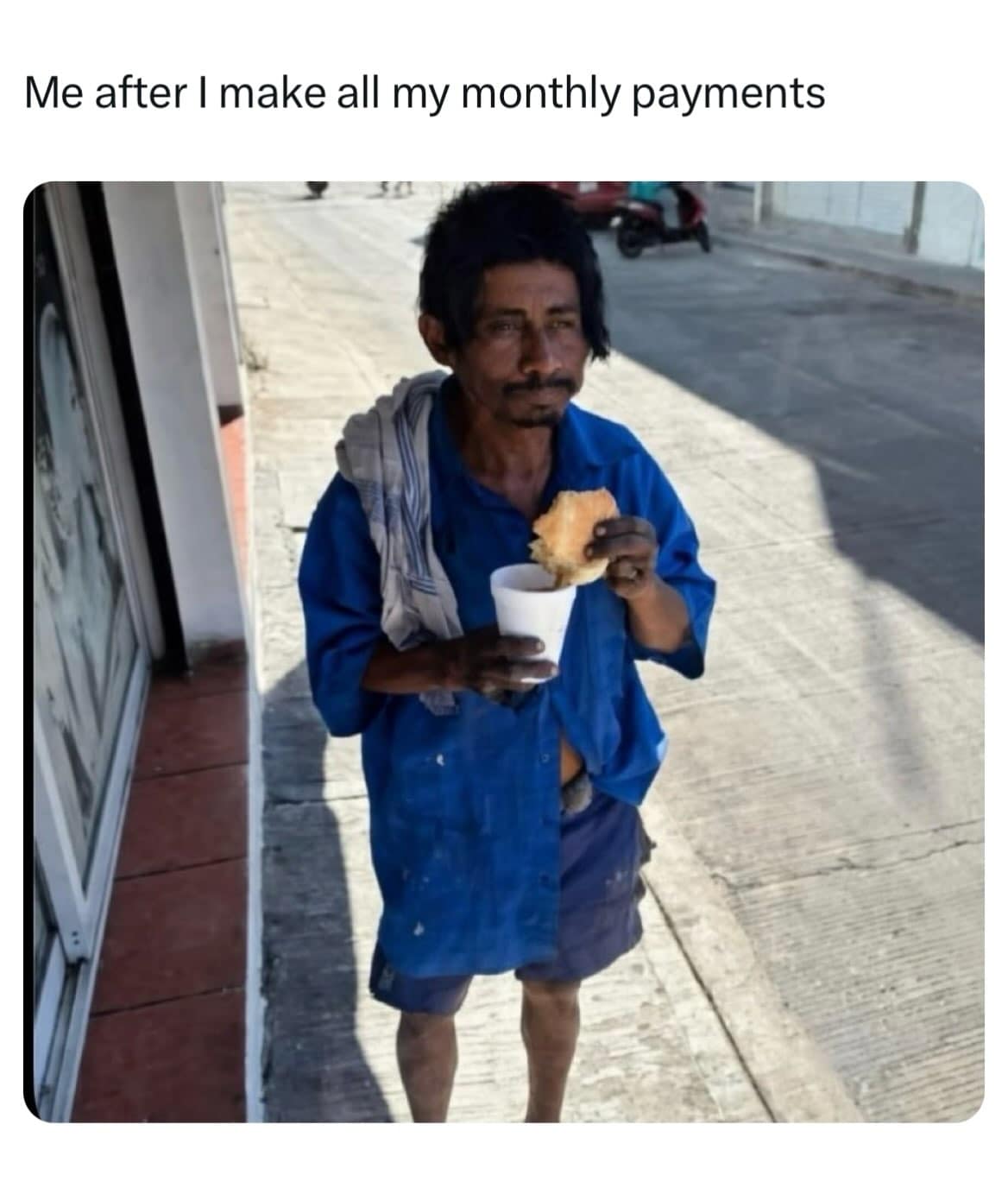 An exhausted-looking man on a curb eating a slice of bread after paying his monthly bills.