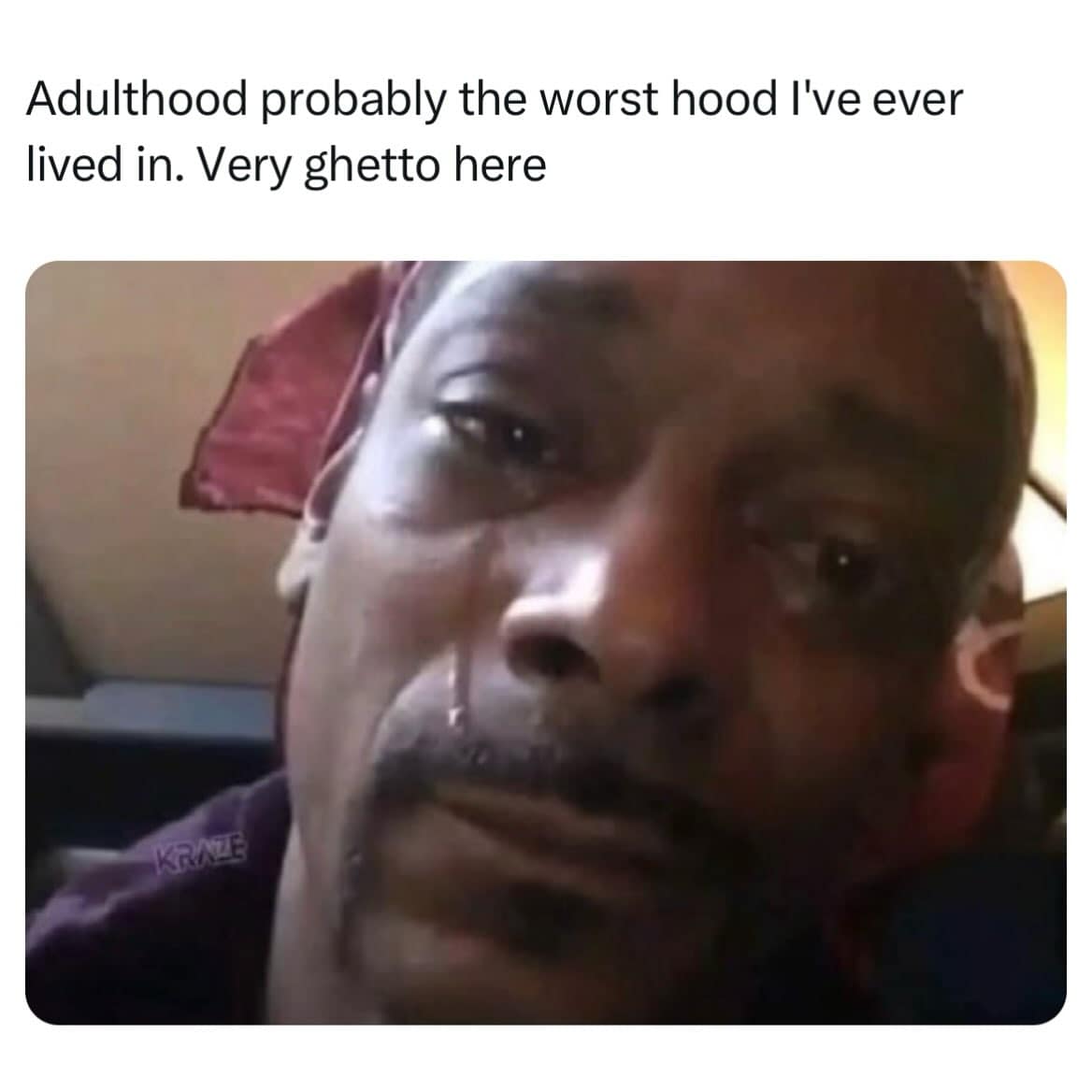 Close-up screenshot of rapper Snoop Dogg shedding a single tear, overlaid with text calling adulthood the worst and most ghetto neighborhood ever lived in.