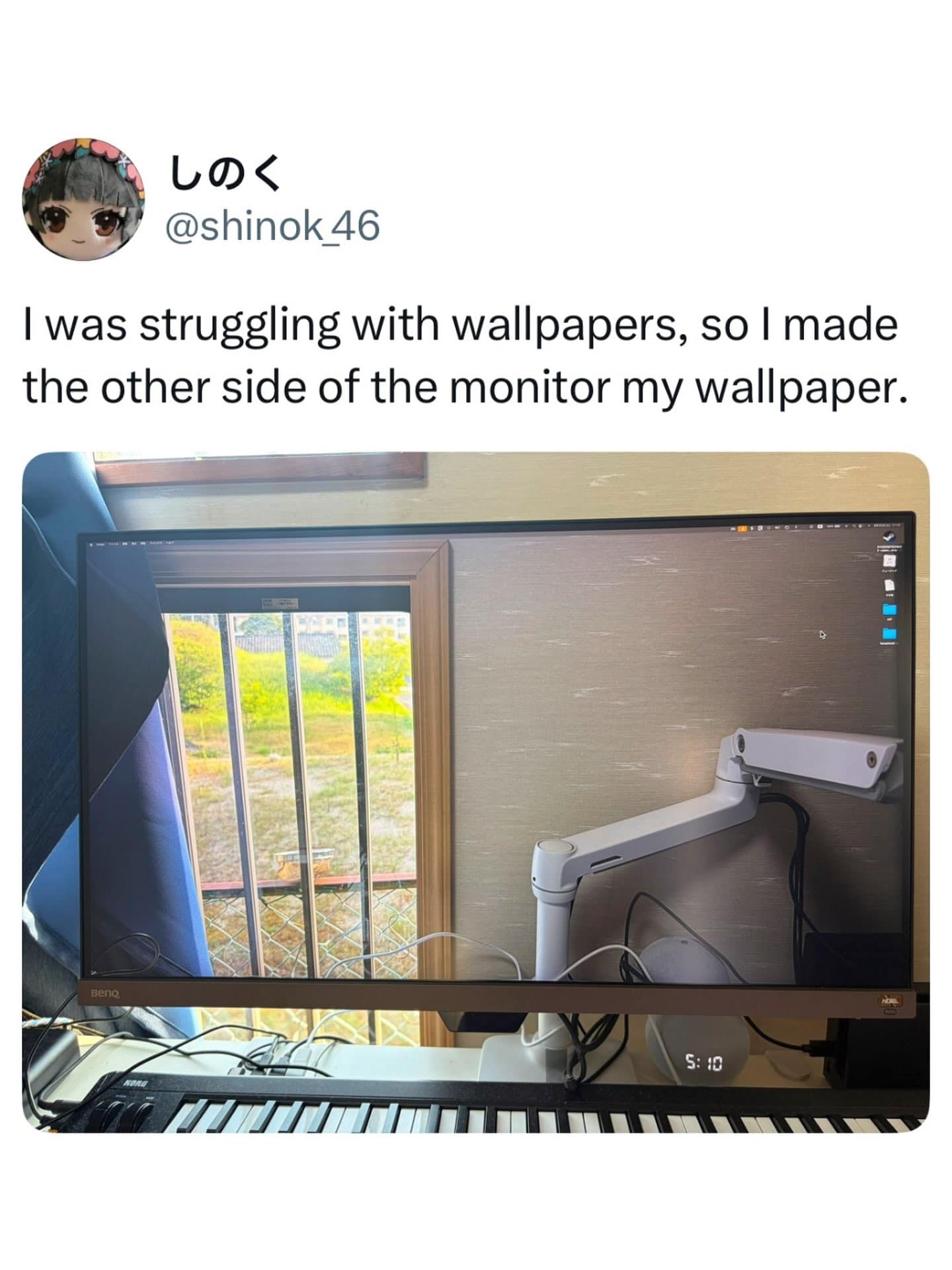 Photo of a desktop computer monitor displaying a custom wallpaper that perfectly mirrors the wall, window, and monitor arm directly behind it to create a transparent optical illusion.