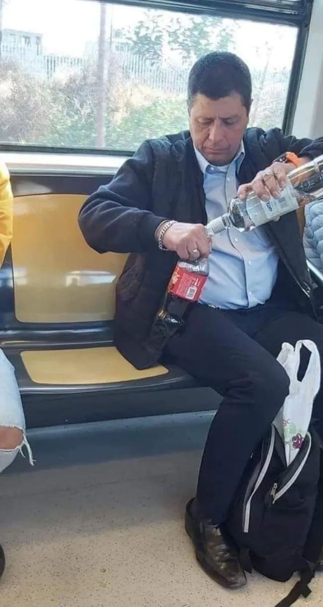 A commuters' survival tactic in the meme dump captures a passenger on a train carefully pouring a large bottle of hard liquor directly into a plastic soda bottle.