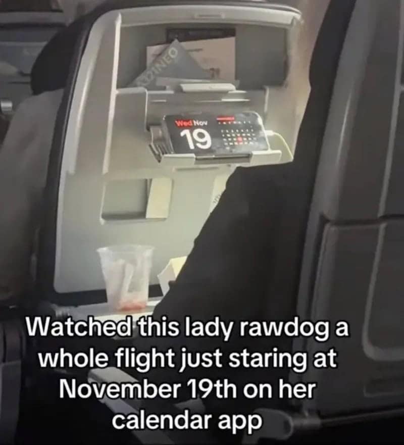 Airplane seatback view of a passenger staring intensely at an iPhone mounted on the seat display running a calendar app frozen on November 19th in a hilarious meme dump post.