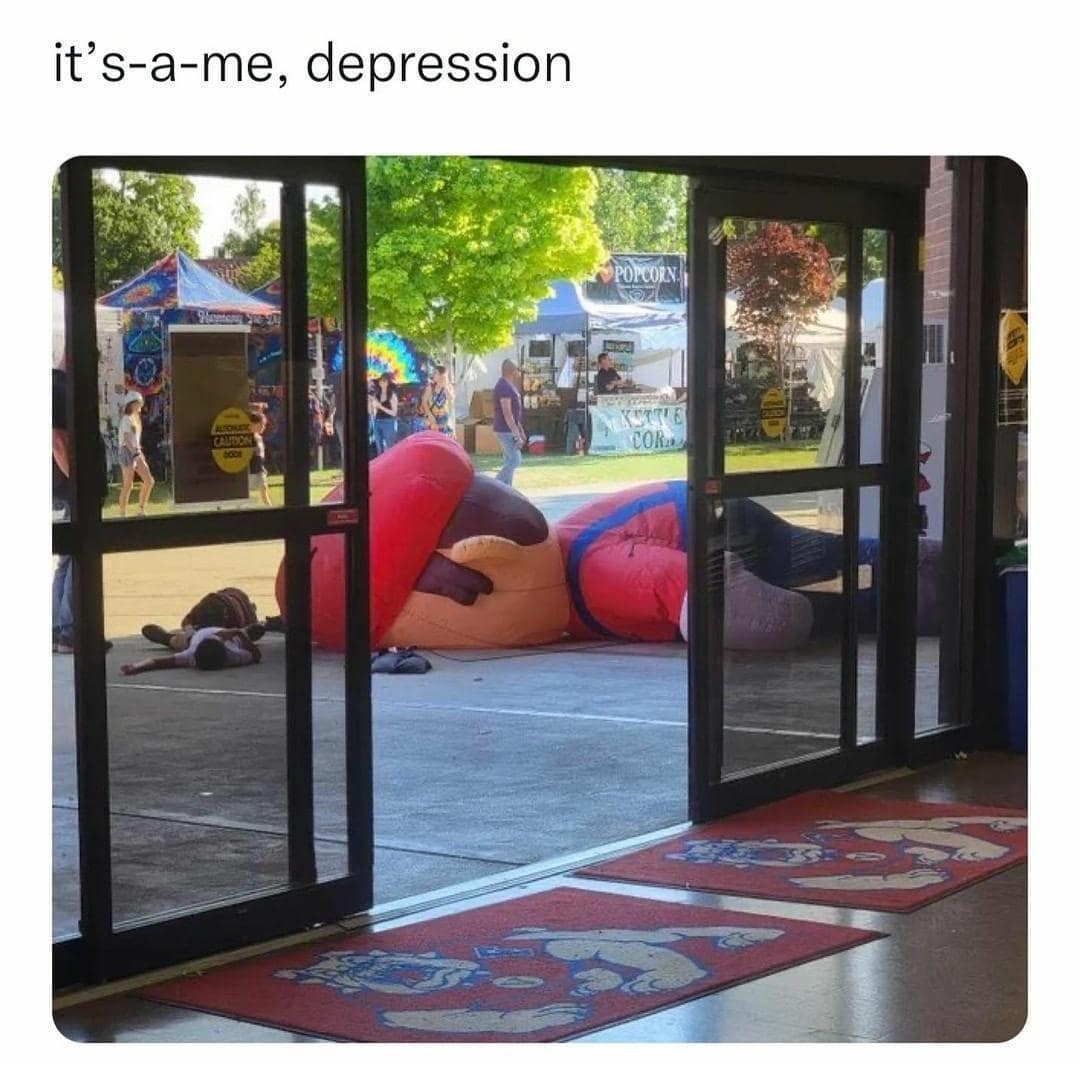 Deflated giant inflatable Super Mario lying face down on the concrete ground outside an event venue labeled as "it's-a-me, depression."