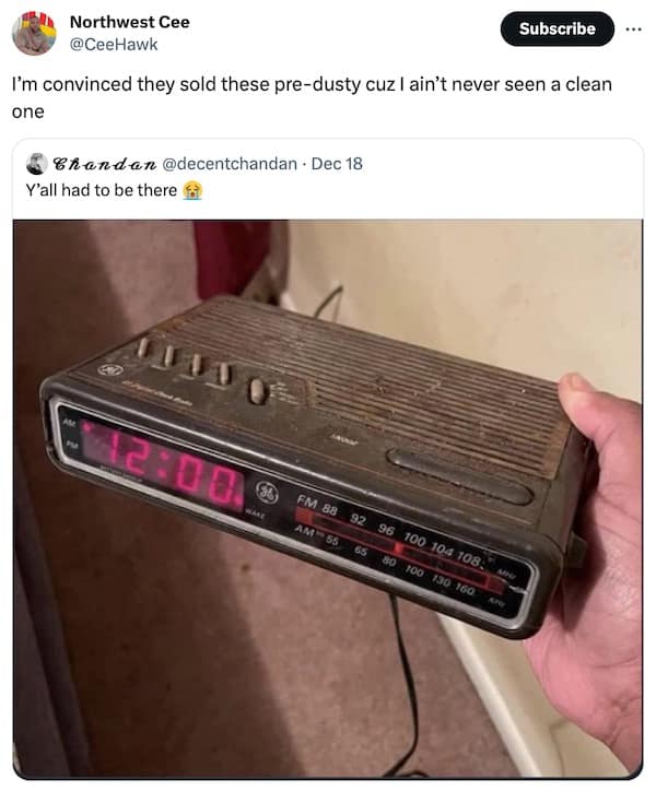Hand holding a vintage General Electric digital alarm clock radio covered in a thick layer of dust, highlighting nostalgic 1990s bedroom aesthetics.