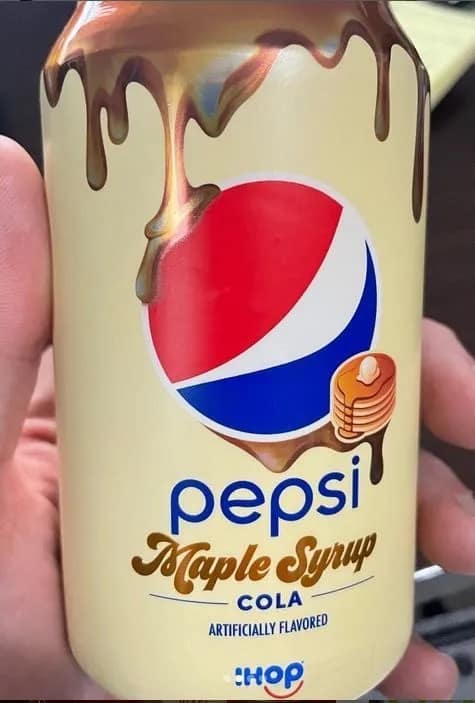 A hand holding a yellow aluminum can of limited-edition IHOP Maple Syrup flavored Pepsi cola dripping with pancake syrup branding.