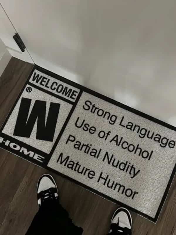 Welcome door mat styled as a video game rating warning for mature humor meme.