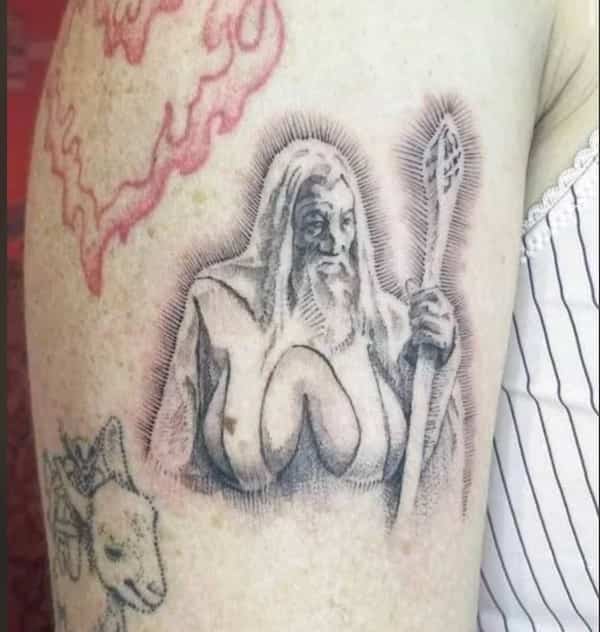 Tattoo artwork showing a wizard character with large cleavage design etched onto a person's upper arm.
