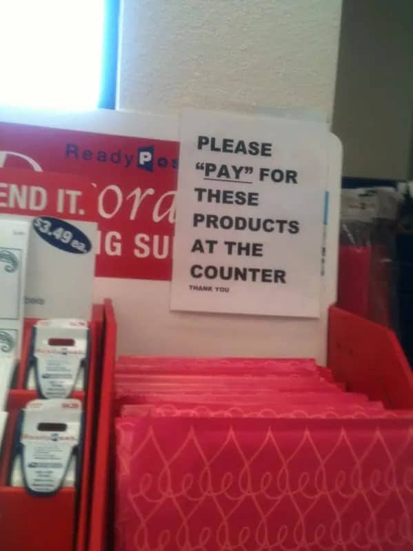 Retail sign directing customers to pay for products with quotation marks surrounding word pay.