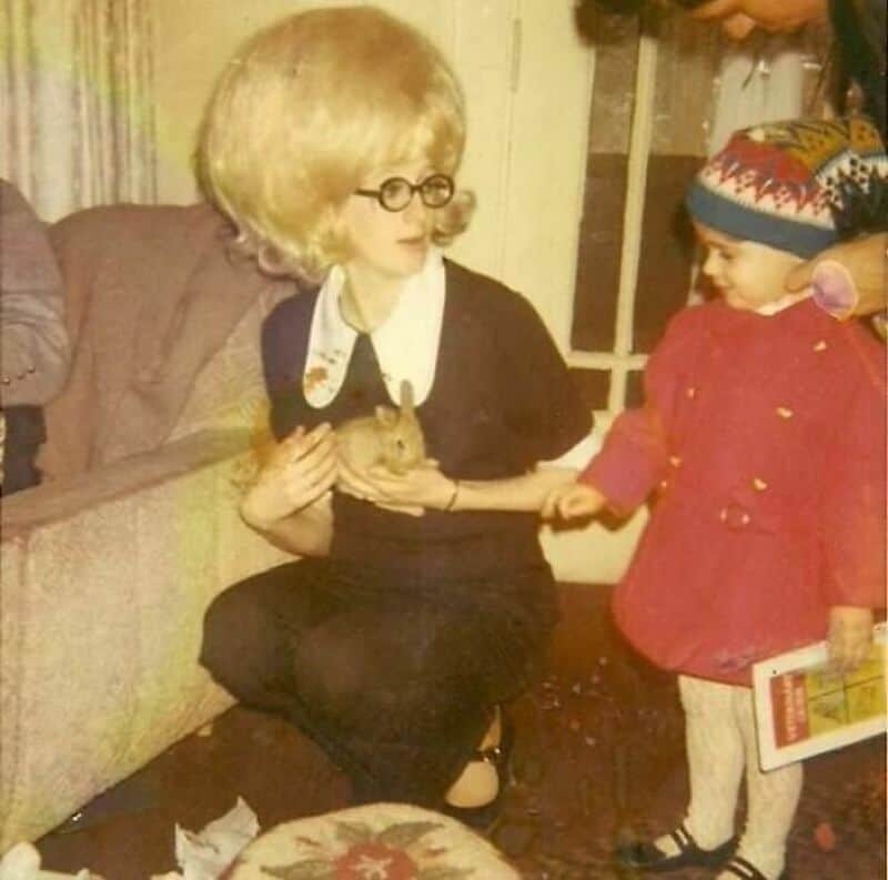 Old school cool woman with giant blonde beehive hair holding a small rabbit.