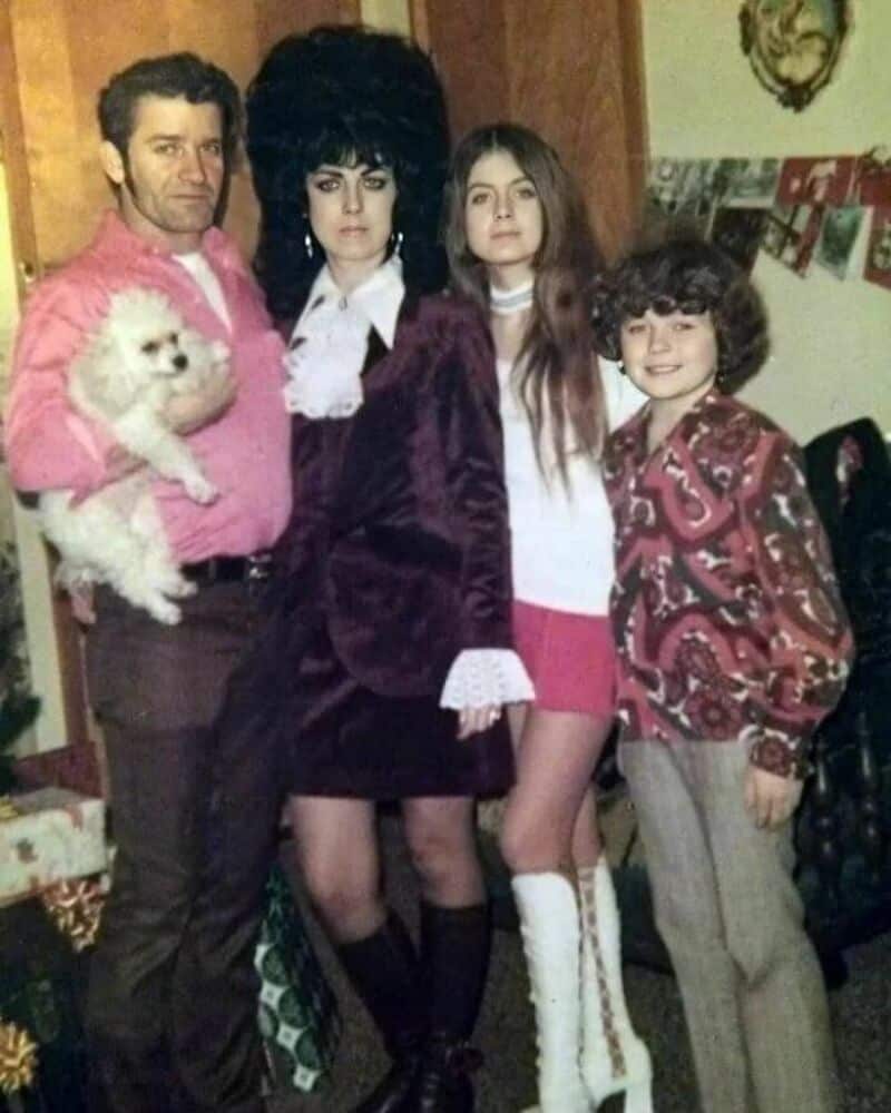 Old school cool family posing together with dark retro clothing and a small dog.