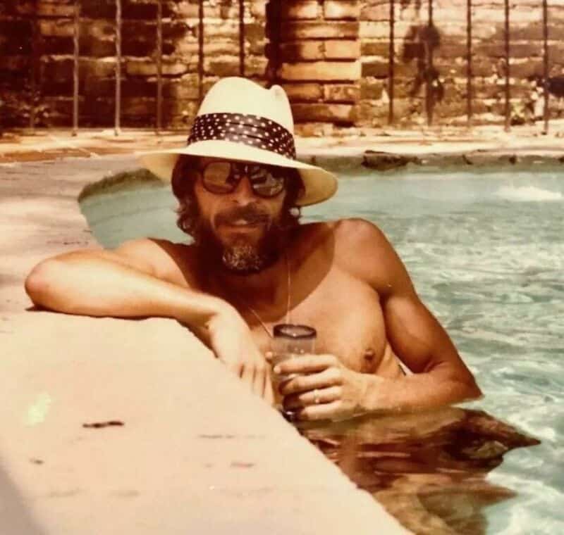 Old school cool man wearing sun hat and sunglasses relaxing inside a swimming pool.