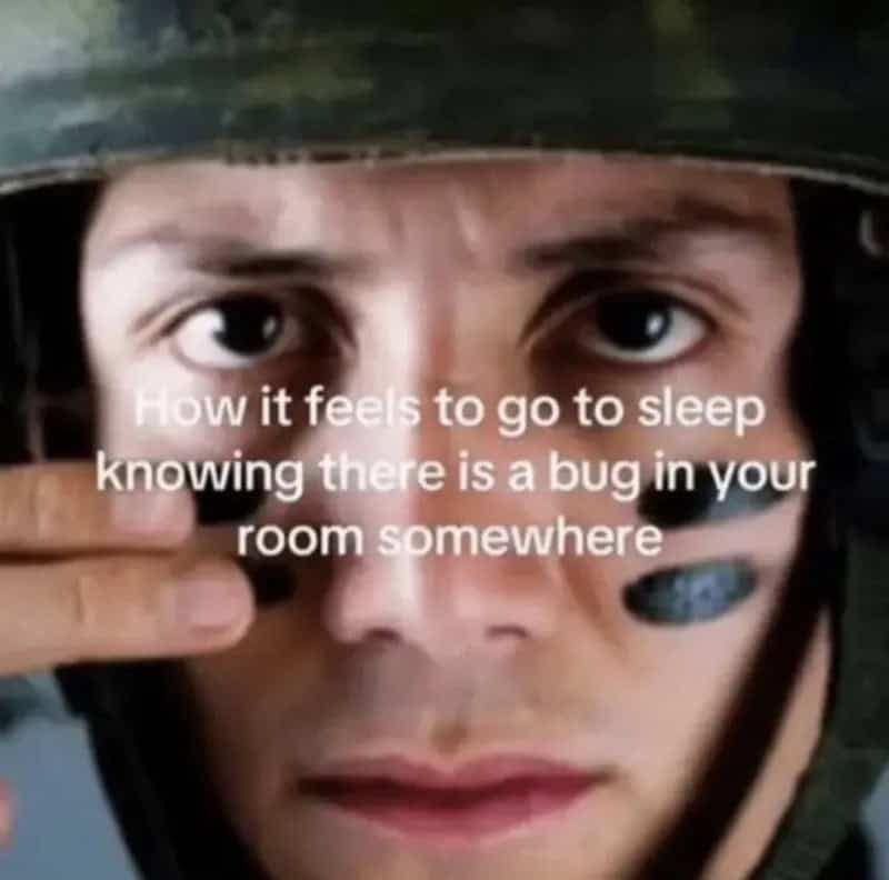 Close-up photo of a soldier in military gear applying black camouflage face paint before going to bed with an untracked insect in the bedroom.