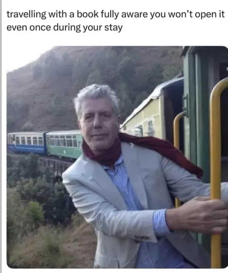 Anthony Bourdain leaning out from a scenic train car, capturing the optimistic decision to pack a paperback book for a trip that you know will never be opened.