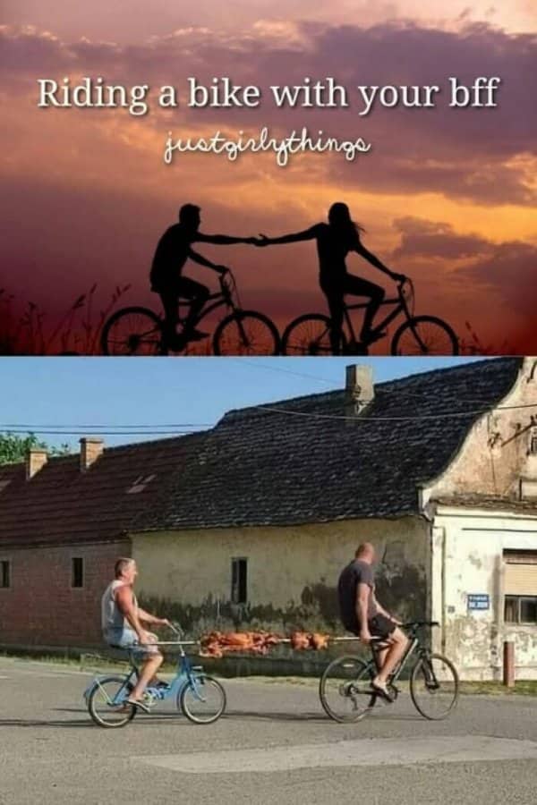 Two men riding bicycles while transporting a whole pig roast on a long wooden spit.