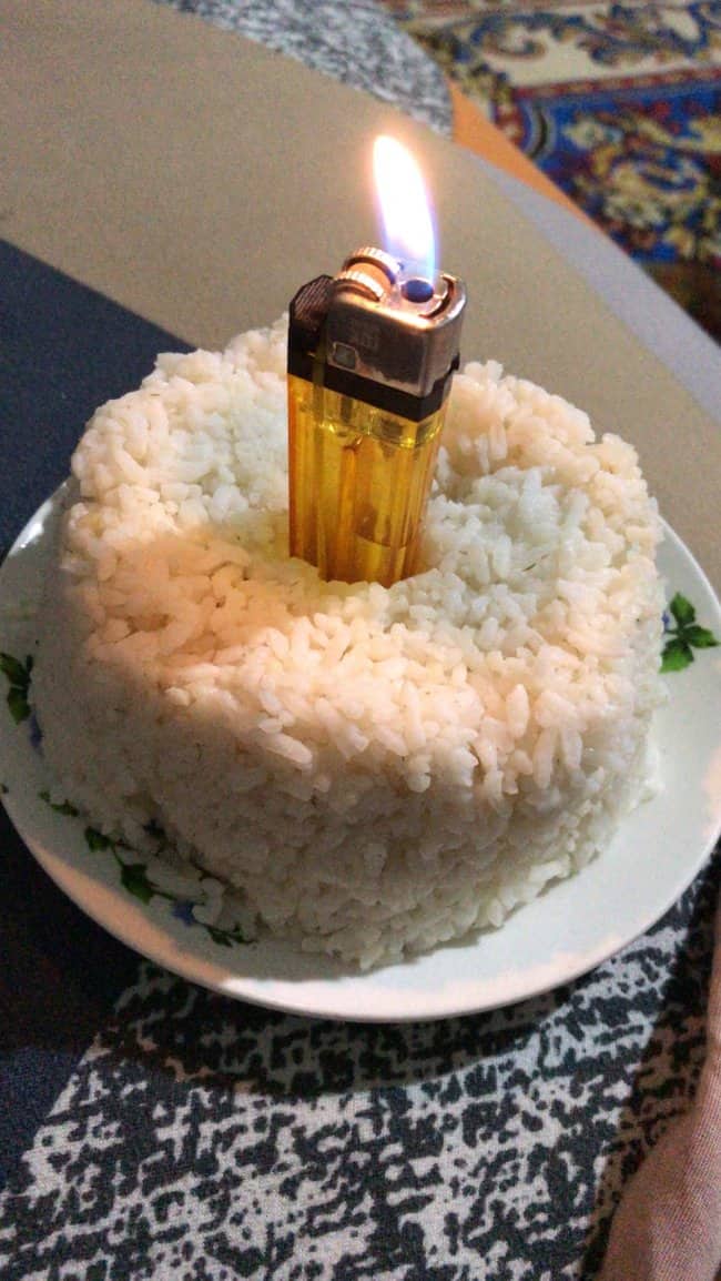 Hilariously depressing birthday cake alternative featuring a lit yellow lighter stuck into plain white rice.