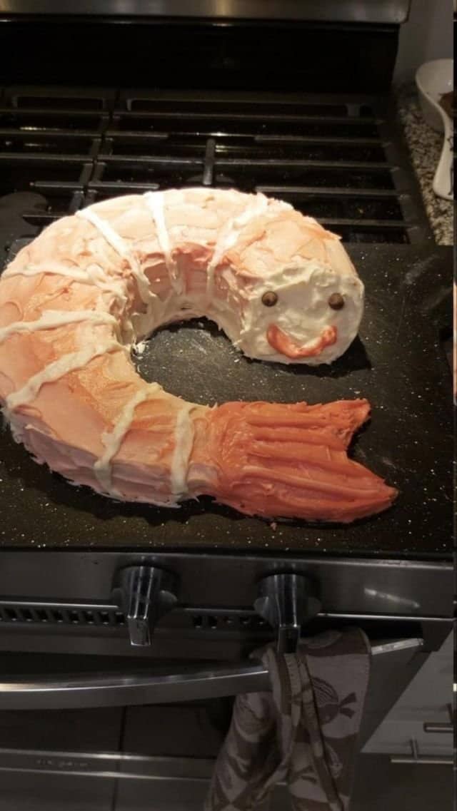 Bizarre homemade cake sculpted and frosted to look exactly like a giant smiling cooked shrimp.