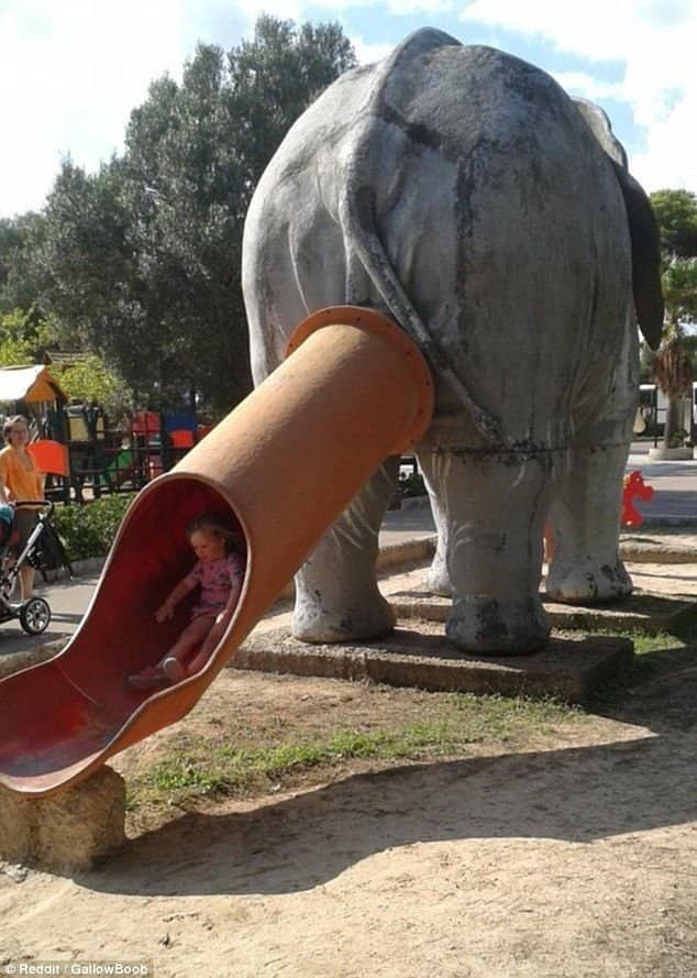 Young child exiting a tube slide emerging directly from an elephant statue representing worst playgrounds.