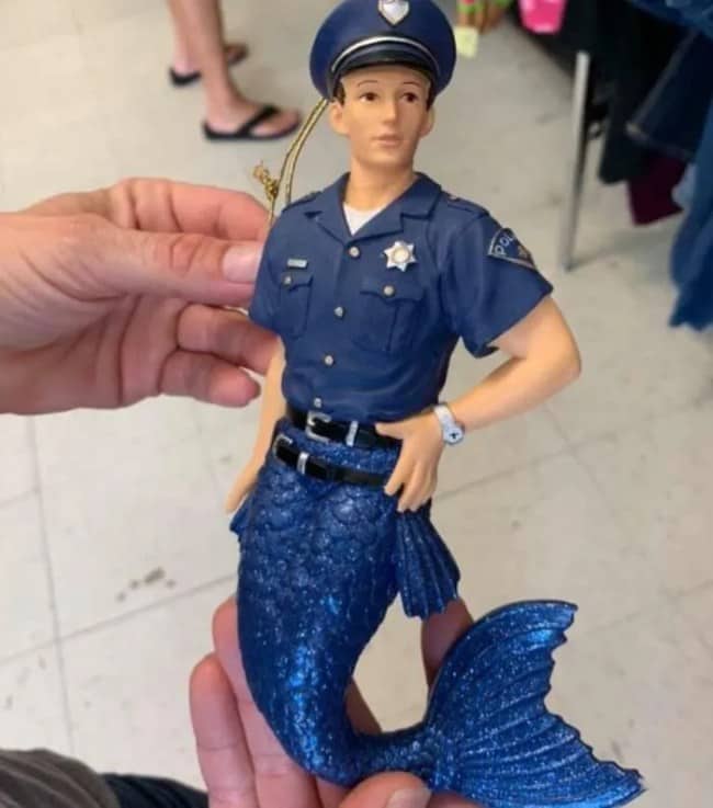 Bizarre thrift store find featuring a male police officer figurine with a blue mermaid tail.