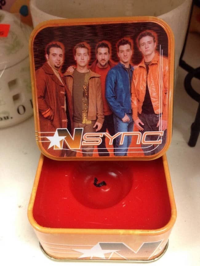 Vintage NSYNC metal container thrift store find opened showing a single piece of lint inside.