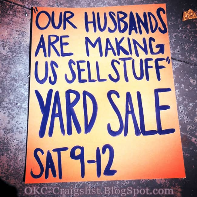 Humorous neon orange yard sale sign stating our husbands are making us sell our stuff.