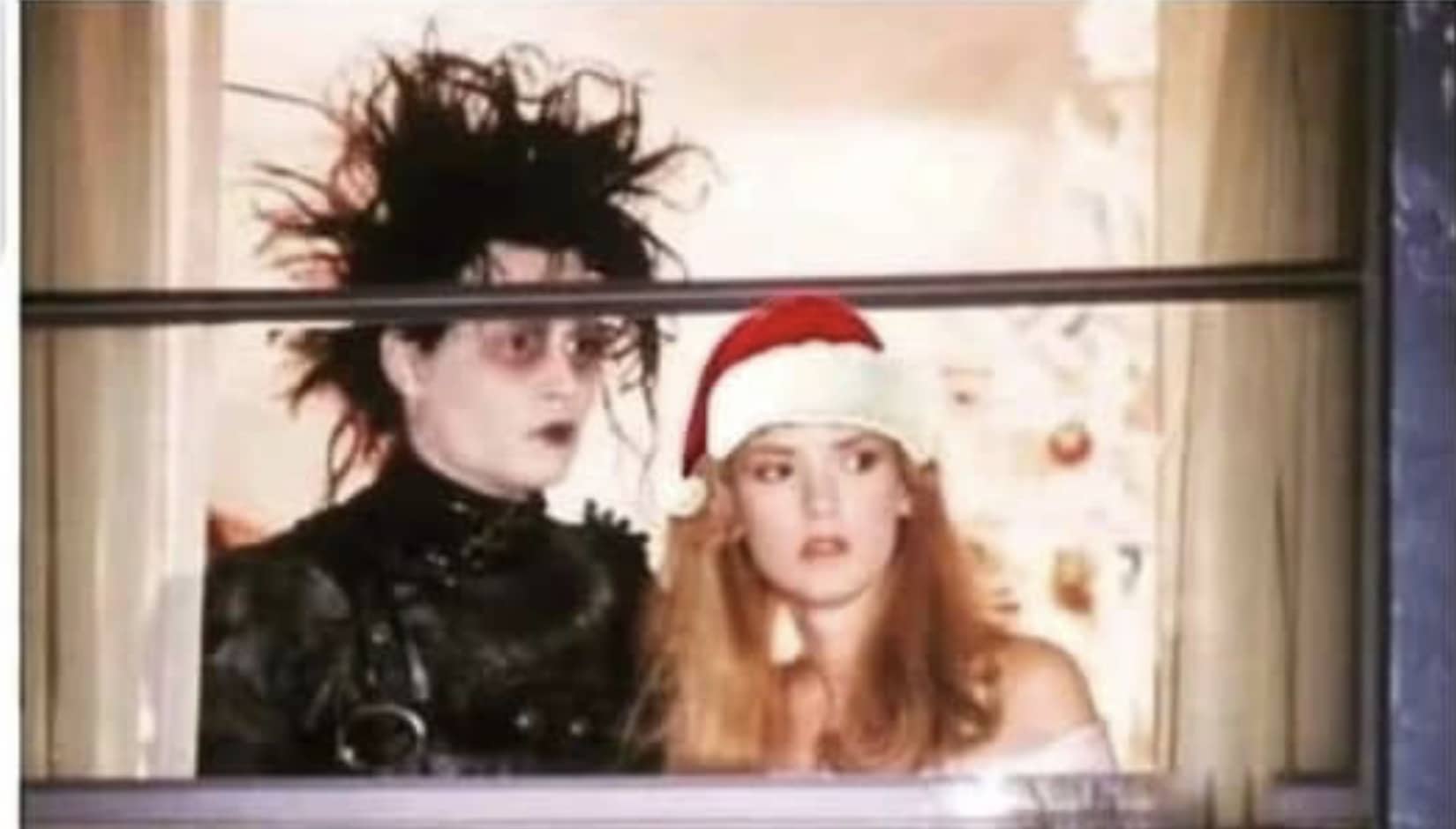 Edward Scissorhands standing with a blonde woman wearing a Santa hat inside a window frame meme.