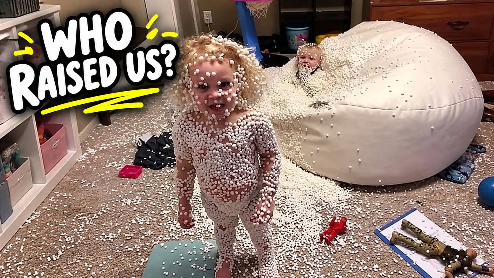 Toddler completely covered in white foam bean bag beads standing next to a mess.