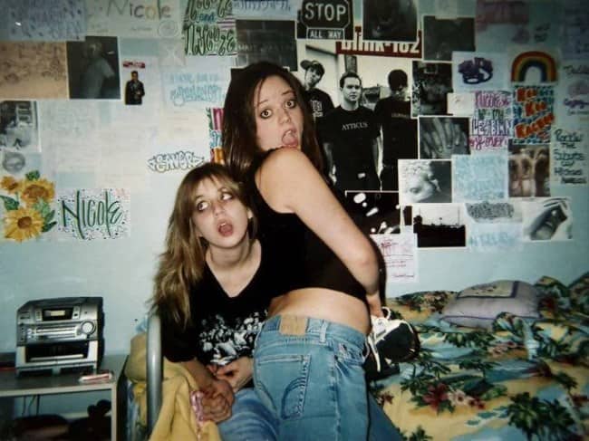 Teenage girls in low rise jeans posing in poster covered 2000s bedroom with boombox.