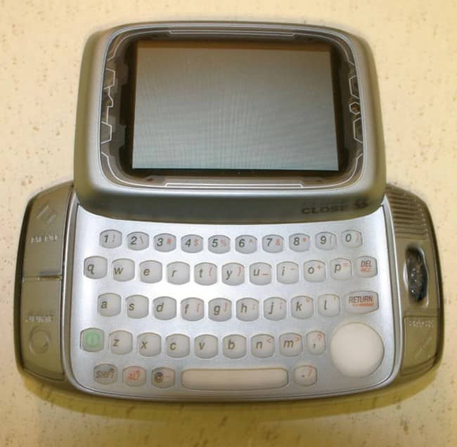 Classic T Mobile Sidekick swivel QWERTY keypad cell phone lying flat on surface.